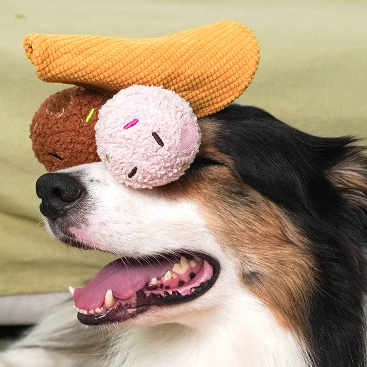 Dog with a toy on its head, featuring a pink ball and brown and orange shapes.